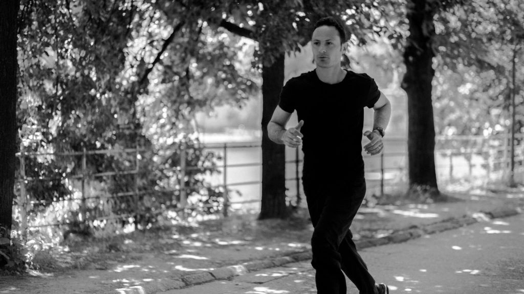Une personne court dans une allée arborée du Jardin du Luxembourg, en noir et blanc.