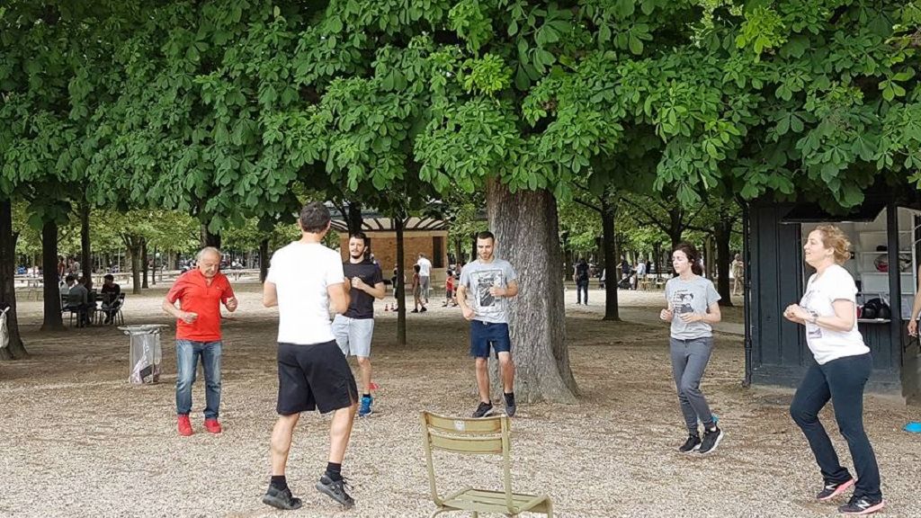 Un groupe fait des exercices de remise en forme sous les arbres, près du Kiosque Sportif.